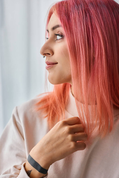 όμορφη χαρούμενη νεαρή γυναίκα σε λευκό πουλόβερ με ροζ ζωηρά μαλλιά ποζάροντας στην κουζίνα και κοιτάζοντας μακριά - Φωτογραφία, εικόνα
