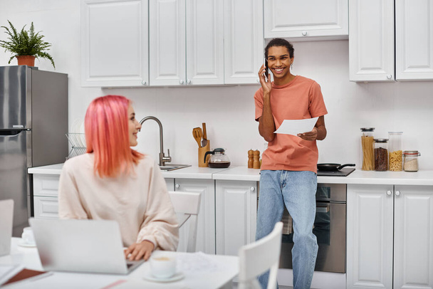 focus on cheerful african american man talking by phone and smiling at his blurred girlfriend - Photo, Image