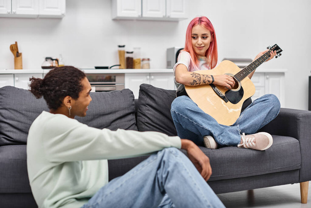 rose cheveux belle femme jouer de la guitare et en regardant son petit ami afro-américain aimant - Photo, image