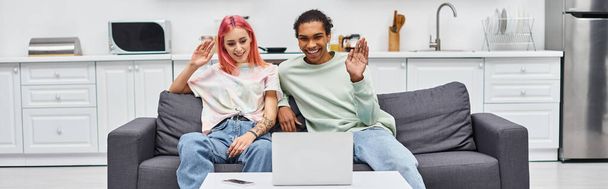 cheerful beautiful multicultural couple waving at laptop camera during video call, banner - Photo, Image