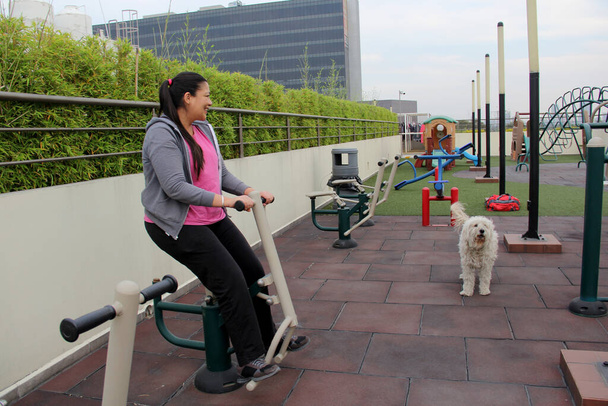 40-летняя латиноамериканка упражняется в саду на крыше своего кондоминиума в сопровождении своей собаки эмоциональной поддержки, чтобы преодолеть депрессию и тревогу. - Фото, изображение
