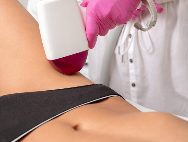 Elos epilaatio karvojen poisto menettely naisten vartalo.Kosmetologi tekee laser nuorentaminen säären kauneushoitola. Poistan ei-toivottuja karvoja. Laitteisto ipl kosmetiikka - Valokuva, kuva