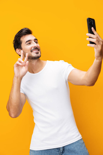 Man space portrait business copy technology selfie toothy eyeglass phone communication cyberspace pointing smartphone mobile lifestyle phone surprise yellow studio happy smile smiling isolated - Photo, Image