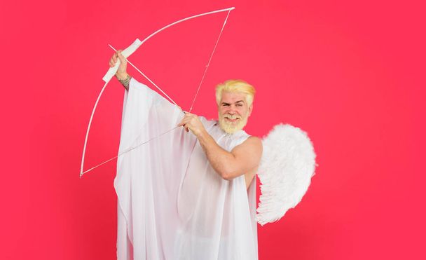 Happy Valentines day. Smiling bearded man in angel costume with bow and arrow. Male cupid in white angel wings with bow and arrow. God of love. Valentines day cupid angel shooting arrows of love - Photo, Image