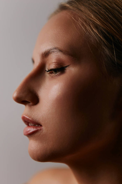 Minimalistische schoonheid portret van een mooi meisje met make-up en emoties op een lichte achtergrond - Foto, afbeelding