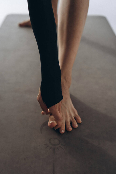 Йогіні тримає її ноги рукою на килимку для йоги - Фото, зображення