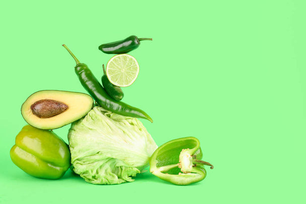 Komposition mit verschiedenen frischen Gemüsesorten auf grünem Hintergrund - Foto, Bild