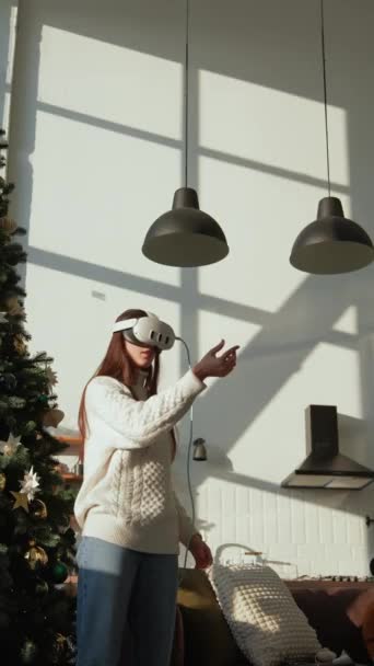 Використовуючи гарнітуру VR, яскрава дівчина насолоджується віртуальною реальністю в сонячній квартирі. Високоякісні 4k кадри - Кадри, відео