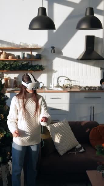 Dans un appartement bien éclairé, une fille vivante explore la réalité virtuelle avec un casque. Images 4k de haute qualité - Séquence, vidéo