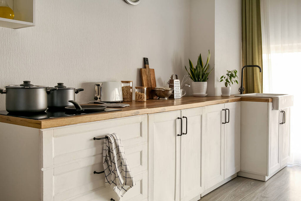 Balcões brancos com panelas de cozinha, utensílios e pia na cozinha moderna - Foto, Imagem