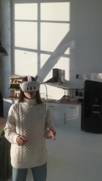 Egy lány 3D virtuális valóságot tapasztal otthon, VR headsetet visel a lakásában. Kiváló minőségű 4k felvételek - Felvétel, videó
