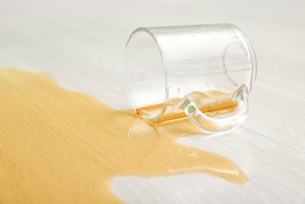 Ξύλινο πάτωμα laminate με αναποδογυρισμένο φλιτζάνι τσάι, closeup - Φωτογραφία, εικόνα