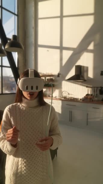 A lakása kényelmében egy lány egy VR headset segítségével elmerül a 3D virtuális valóságban. Kiváló minőségű 4k felvételek - Felvétel, videó