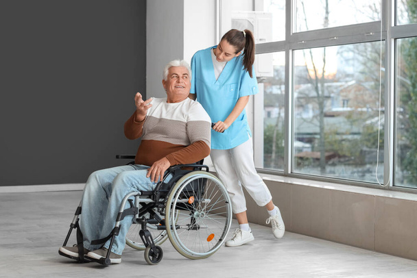 Starší muž na invalidním vozíku a zdravotní sestra v nemocnici - Fotografie, Obrázek