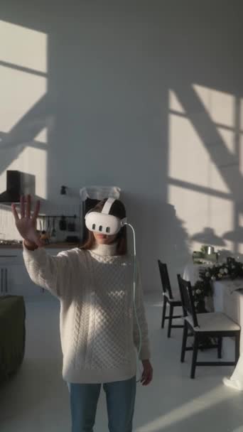 En casa en su apartamento, una chica experimenta la realidad virtual 3D con un auricular VR. Imágenes de alta calidad 4k - Metraje, vídeo
