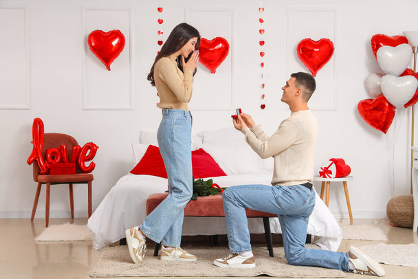 Молодий чоловік пропонує своїй дівчині в спальні. Святкування Дня святого Валентина - Фото, зображення