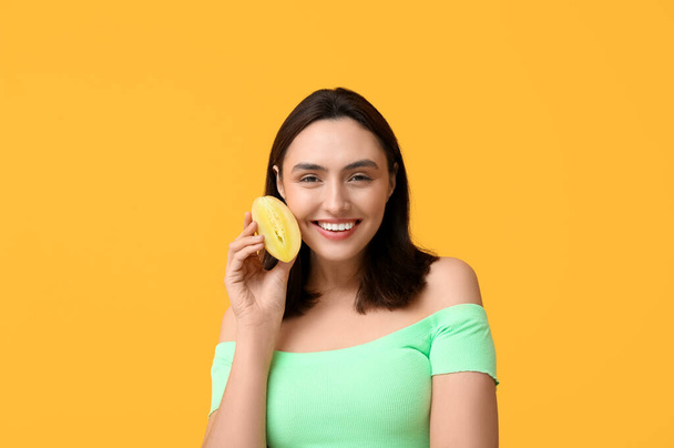 Piękna młoda kobieta z owocami chikoo na żółtym tle - Zdjęcie, obraz