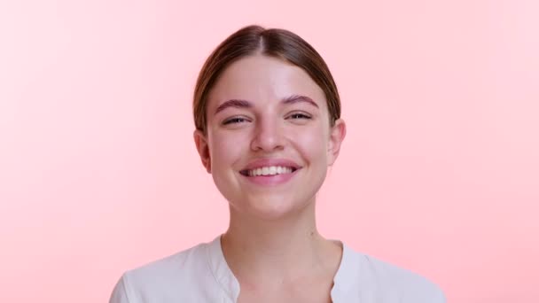 Caucasian woman playfully blows glitter into the air, eyes twinkling with delight against the pink backdrop. Her playful gesture creates a magical atmosphere, capturing the essence of whimsy and joy. - Footage, Video