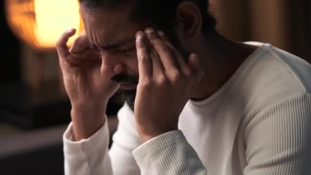 El hombre indio se representa con una expresión triste, experimentando la incomodidad de un dolor de cabeza. La imagen captura la tensión emocional y física, creando una escena reflexiva en el entorno tranquilo. - Metraje, vídeo
