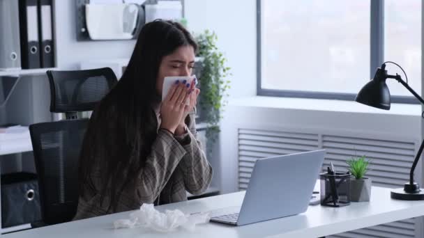 Businesswoman with a cold uses a tissue while working with a laptop. This image portrays the challenges of balancing work responsibilities while managing health issues. - Footage, Video