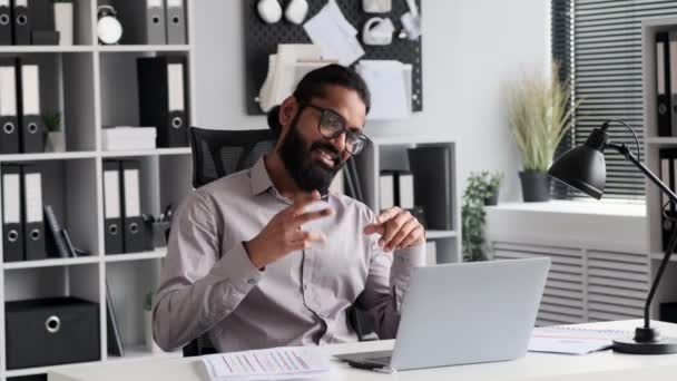 Indian businessman taking a break in the office, engages in a cheerful video call. clothed in office wear, upbeat expressions convey a sense of joy and connection during the break. - Footage, Video