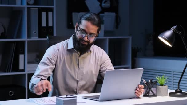 Pozitivní indický podnikatel pilně pracuje v kanceláři. Oblečen do formálního oděvu, naviguje úkoly s odhodlaným zaměřením, ztělesňující oddanost a profesionalitu. - Záběry, video