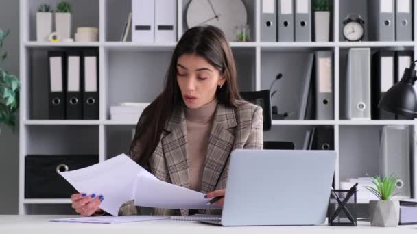 Radiating positivity, a cheerful Caucasian woman smiles as she engages in paperwork at the office. This image captures the joyful and optimistic spirit she brings to the workplace - Footage, Video