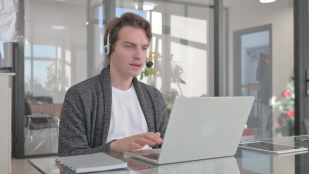 Mladý muž s sluchátky mluvit online se zákazníkem v call centru - Záběry, video