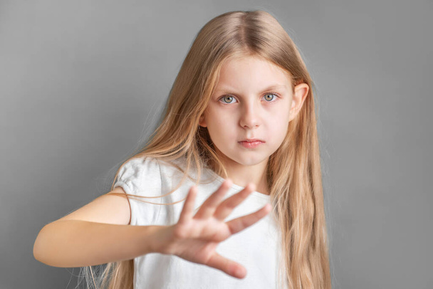 Een klein meisje met een teken van protest of weigering met haar hand. - Foto, afbeelding