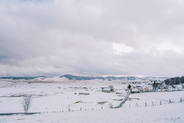 Маленькая снежная деревня с пастбищами в горной долине. Высокое качество фото - Фото, изображение