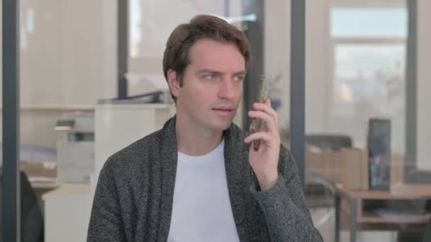 Portrét ležérního mladého muže mluvícího po telefonu, vyjednávání - Záběry, video