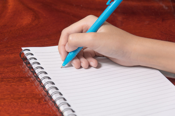 Χέρι γράφοντας στο σημειωματάριο, ξύλο backgroud - Φωτογραφία, εικόνα