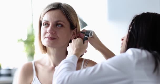 Отоларинголог осматривает женское ухо с помощью отоскопа. Концепция нарушения слуха у взрослых - Кадры, видео
