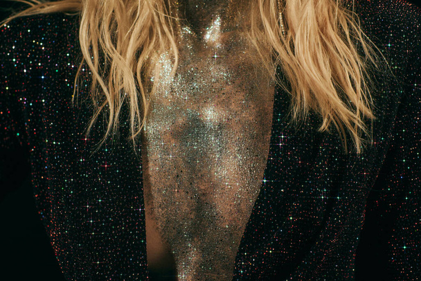 cropped shot of woman with sparkling glitter on chest and jacket with sequins on black background - Photo, Image