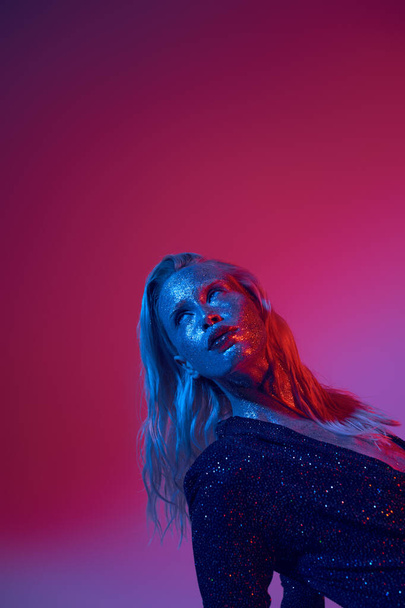 blondi ja tyylikäs nainen glitter kasvot ja kiiltävä asu poseeraa elinvoimainen neon tausta - Valokuva, kuva