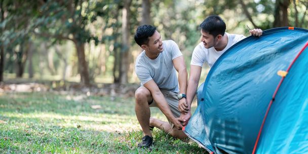 LGBTQIA Gay couple camping together in woods for holidays and helping set up a tent together. - Photo, Image