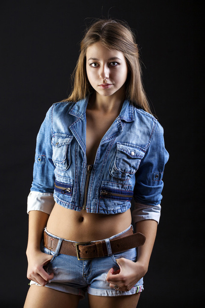 Portrait young girl in a blue jeans jacket and shorts in dark st - Fotó, kép