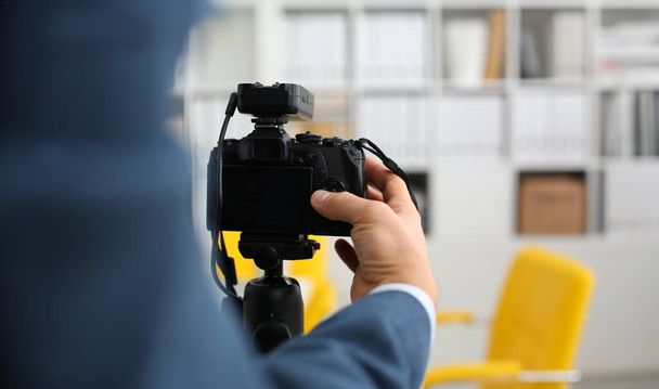 Takım elbiseli erkek silah kamera tripod promo videoblog veya fotoğraf oturumu ofis portre yapmak için mount. Vlogger küme ayarlama ve iş teklif promosyon selfie bilgileri göstermek için görüntü kalitesini kontrol edin - Fotoğraf, Görsel