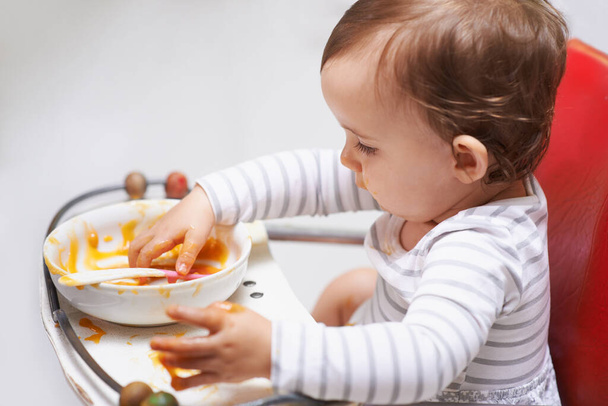 Comer, purê e menina bebê na cadeira com comida vegetal para o desenvolvimento infantil em casa. Bonito, nutrição e criança ou criança com fome desfrutando de almoço saudável, jantar ou jantar em casa - Foto, Imagem