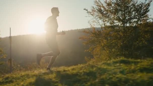 Ευτυχισμένος Καυκάσιος άνδρας άνδρας τύπος αθλητής δρομέας δρομέας τρέξιμο τρέξιμο μαραθώνιος κατάρτισης υγιή ενεργό τρόπο ζωής τρέχει υψηλό βουνό προπόνηση σώμα άσκηση γυμναστικής ανατολή του ήλιου φως του ήλιου σε εξωτερικούς χώρους φύση - Πλάνα, βίντεο