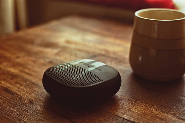 closeup photo of a black wireless speaker on a wooden table - Photo, Image