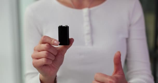 Young woman holds battery in hand and gives thumb up gesture. Female demonstrates standard battery emphasizing features and durability and environment protection - Footage, Video