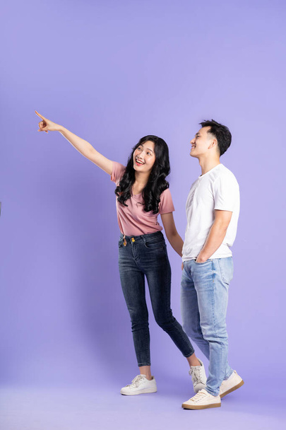 полное изображение азиатской пары, позирующей на фиолетовом фоне - Фото, изображение
