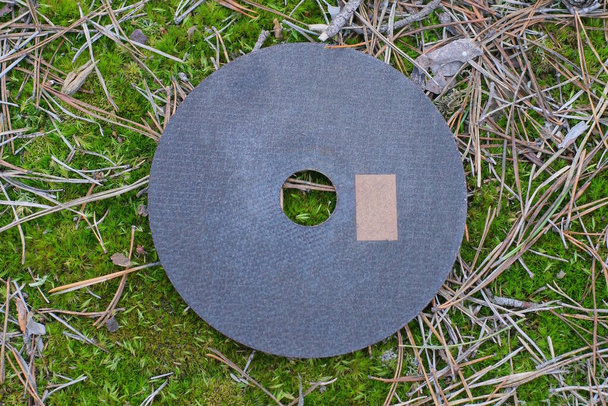 one black cutting wheel for an angle grinder lies on green moss on the street - Photo, Image