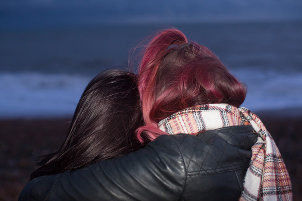 Primer plano de las mujeres abrazándose en la playa al anochecer
 - Foto, Imagen