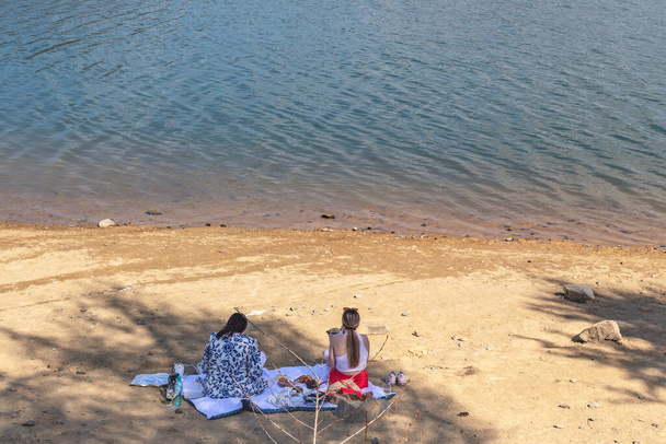 COLIBICA, ROMANIA - 1 Mayıs 2023: Kimliği belirsiz genç kadınlar Colibica Gölü sahilinde piknik yaptılar. - Fotoğraf, Görsel