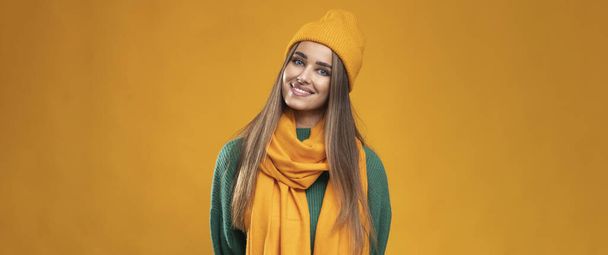 Πολύ θετική νεαρή γυναίκα με πορτοκαλί καπέλο και μαντήλι σε απομονωμένο φόντο. - Φωτογραφία, εικόνα