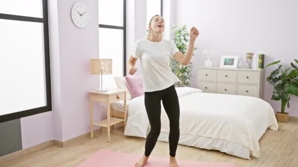 Uma mulher adulta jovem pratica ioga em um quarto espaçoso, olhando relaxado e focado em um ambiente doméstico contemporâneo. - Filmagem, Vídeo