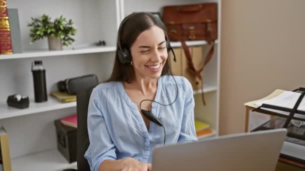 Glowing young hispanic woman is the picture of success in business - effortlessly juggles work, smiling during a video call at her office - Footage, Video