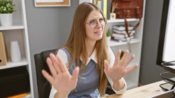 Fiatal szőke irodai munkás, aki elutasító tenyérrel mutogatja a stop gesztust, undorító félelmet és tagadást visel - munkahelyi betiltva - Felvétel, videó